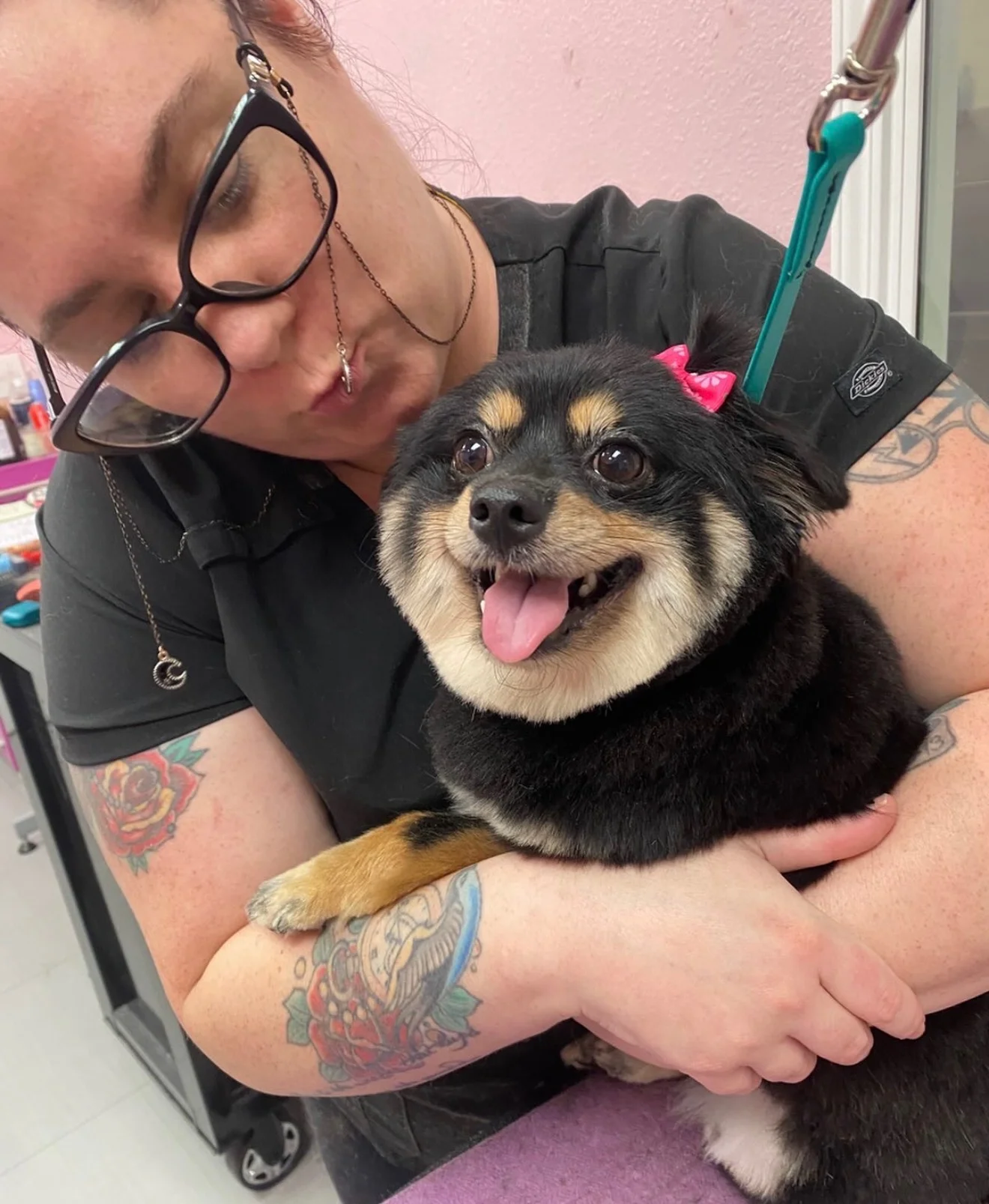 A groomer holding a smiling small black-and-tan dog in the shop